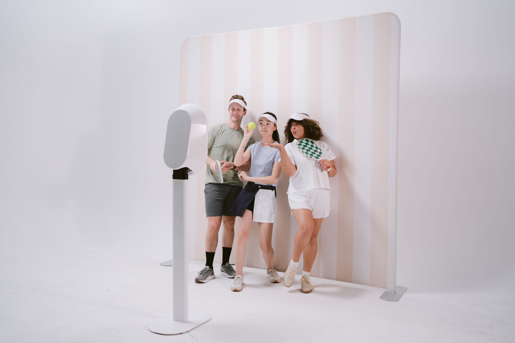 Digital photo booth with guests posing in front of a striped event backdrop